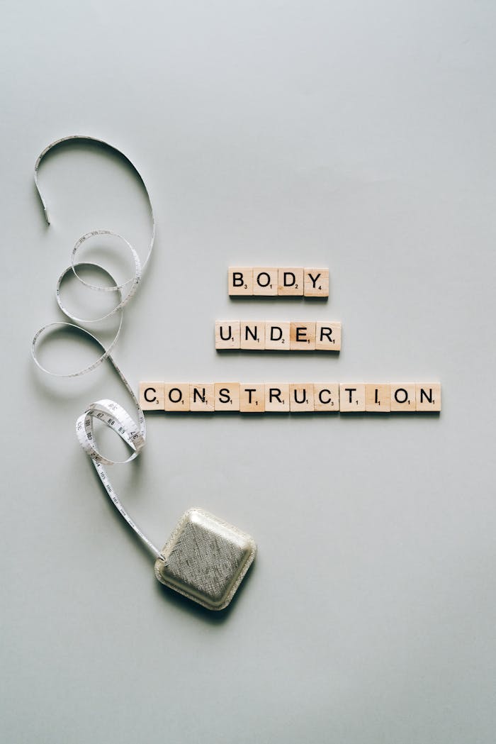 Inspiring fitness concept with 'Body Under Construction' in Scrabble tiles and a tape measure.